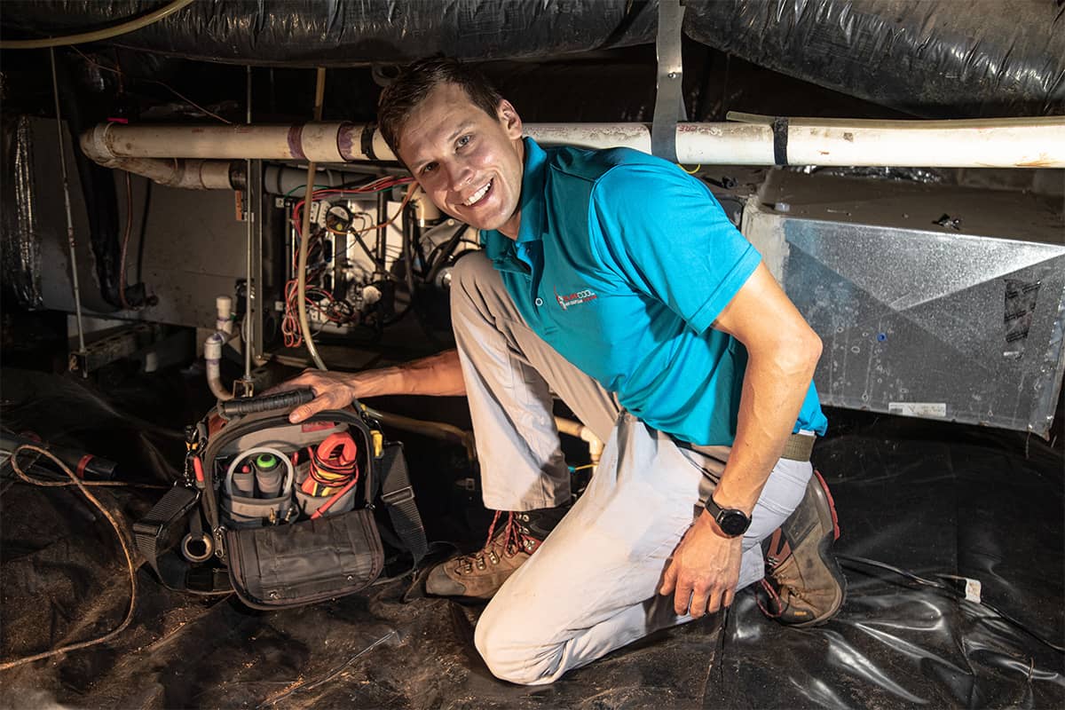 Super Cool Air Conditioning & Heating worker smiling with tools near a duct
