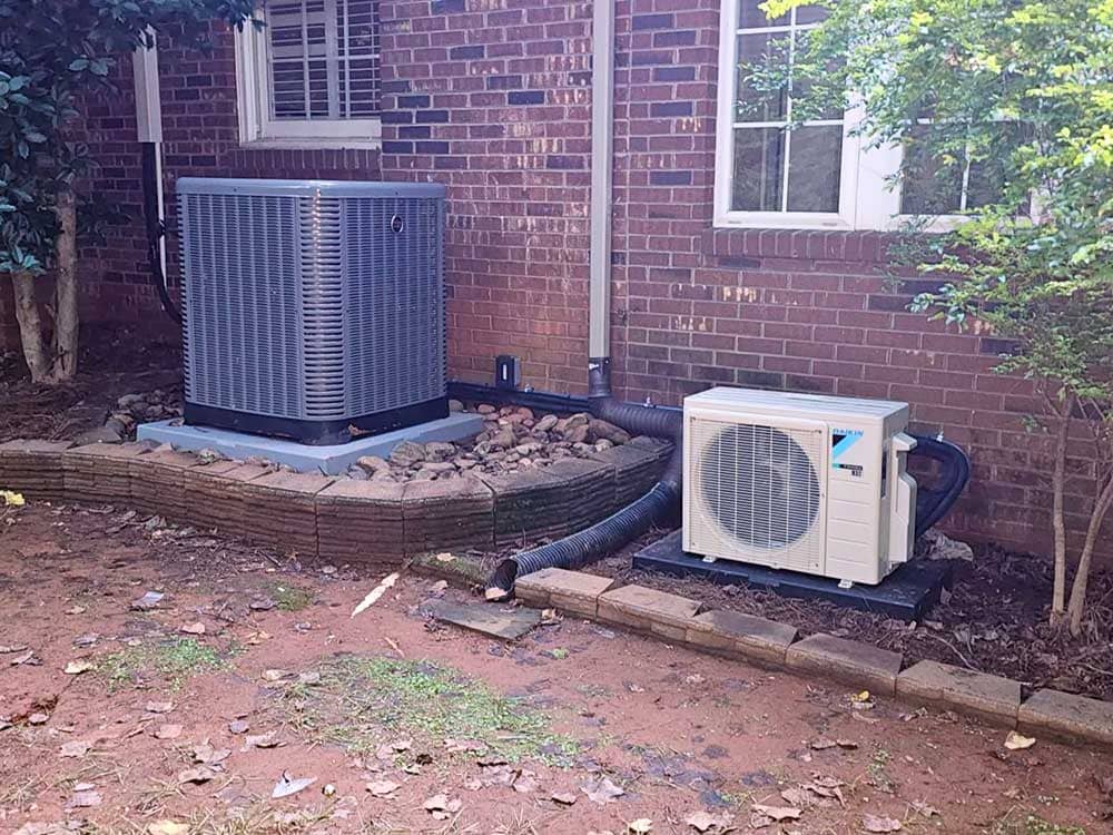 residential HVAC units next to a brick house