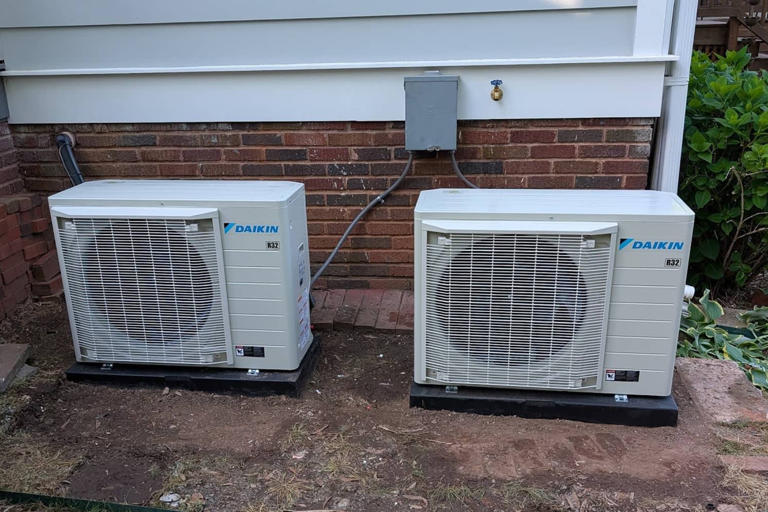 two daikin heat pumps installed outside a house