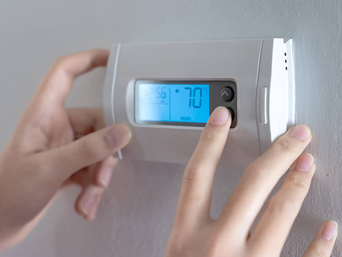 hands turning a digital thermostat down