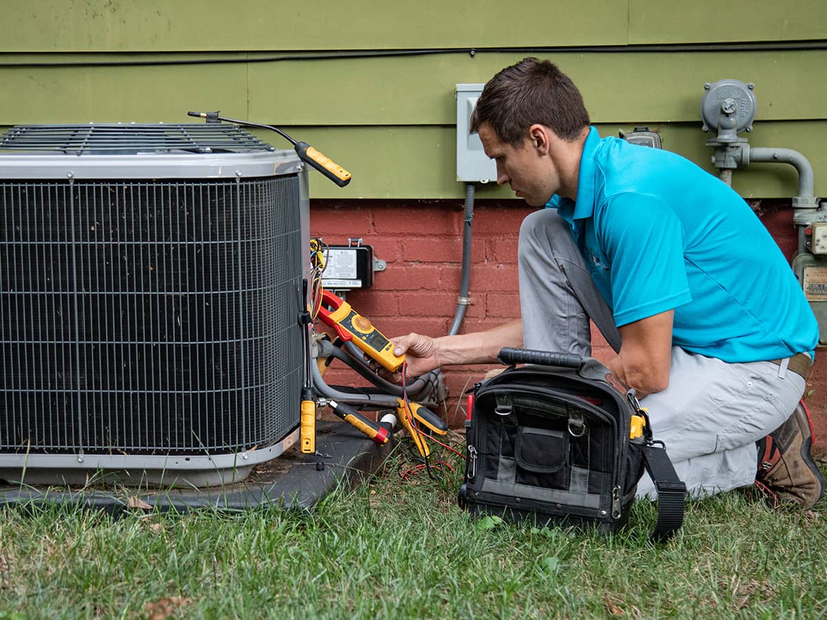 worker in blue shirt checking an HVAC unit