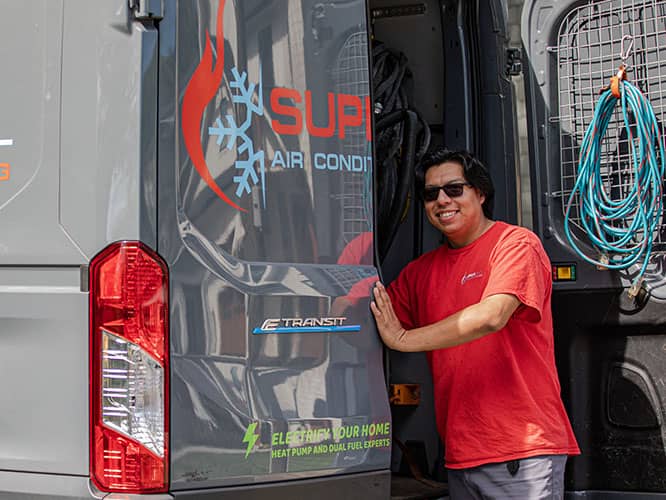 worker in red shirt smiling while grabbing something from the back of the Super Cool Air Conditioning & Heating van